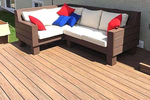 Une terrasse avec un canapé contenant des coussins bleus et rouges 