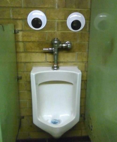 Des gros yeux au dessus d'une toilette à pipi 