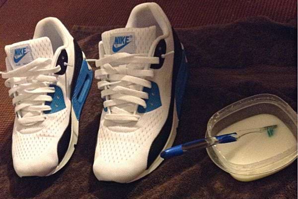 Une paire de Nike Air Max 1 avec une toute petite bassine d'eau et une brosse à dents à l'intérieur