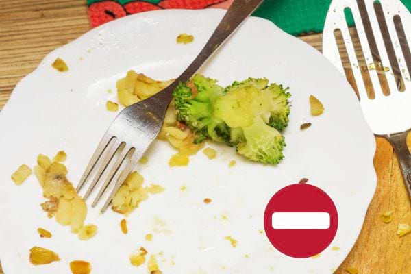 Des restes d'aliments qui reste dans une assiette blanche avec une fourchette à l'intérieur