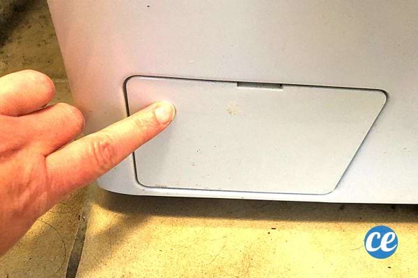 Une personne montrant où se trouve le filtre de la machine à laver