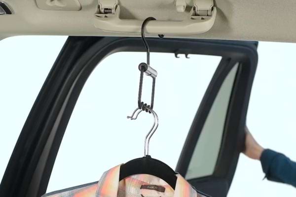 Plusieurs cintres qui sont accrochés sur une poignet de maintien dans la voiture 