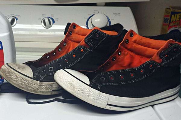 Une paire de basket Converse noir sale et propre avec de l'orange à l'intérieur