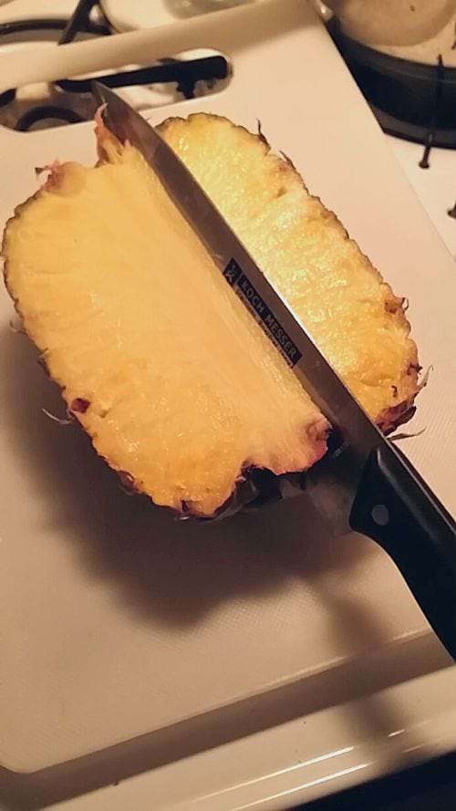 Une personne qui coupe un ananas en deux