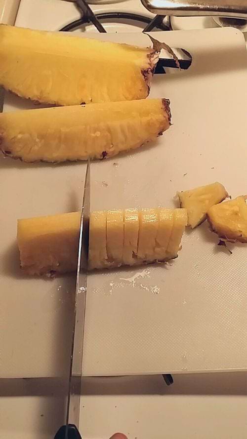 Une personne qui un ananas en tranches