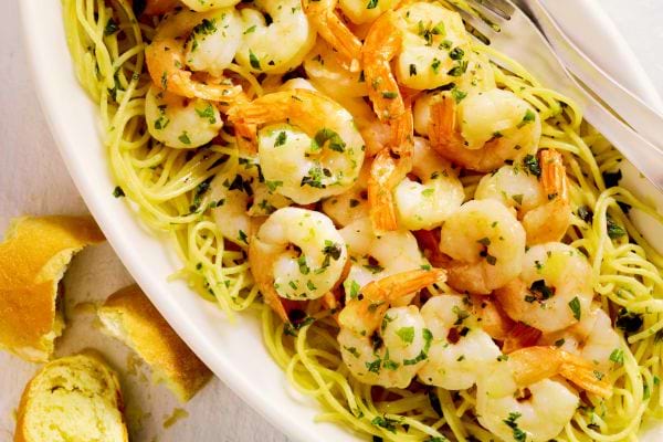 Un plat remplie de spaghettis avec des crevettes par-dessus 