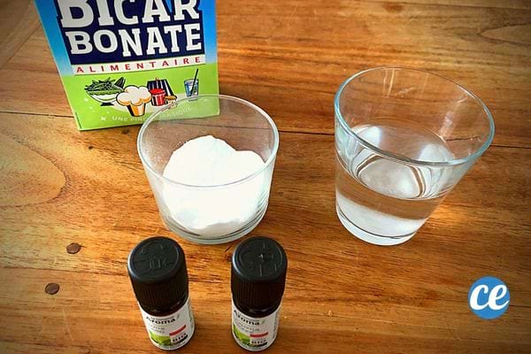 Deux verres avec un remplie de bicarbonate et l'autre d'eau avec deux huiles essentielles juste devant