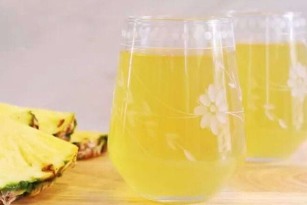 Deux verres remplis d'une eau aromatisée jaune avec des morceaux d'ananas