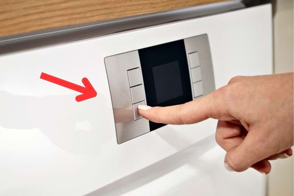 Une femme qui appuie sur le bouton d'un programme de lave-vaisselle