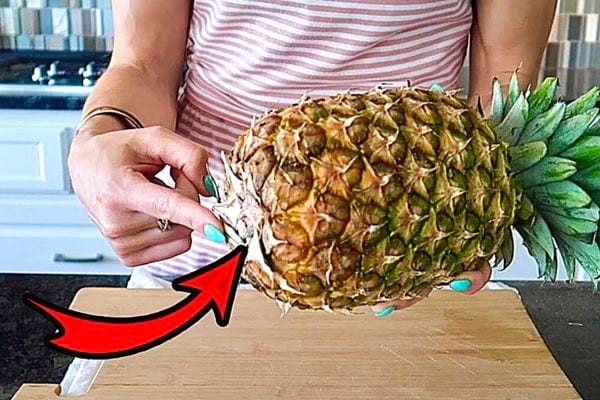 Une femme avec du vernis bleu ciel tenant un Ananas 