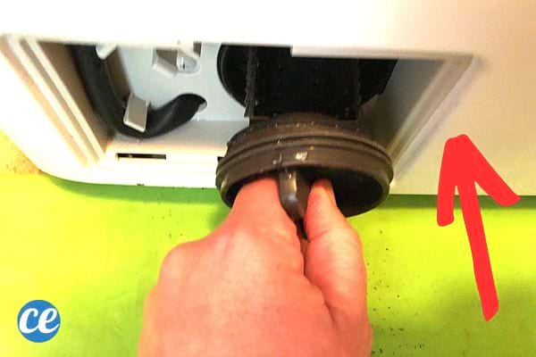 Une personne qui remets le filtre d'une machine à laver dans son compartiment