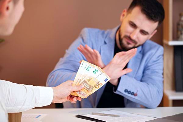 Un homme refusant une liasse de billet de 50 euros que lui passe un autre homme 