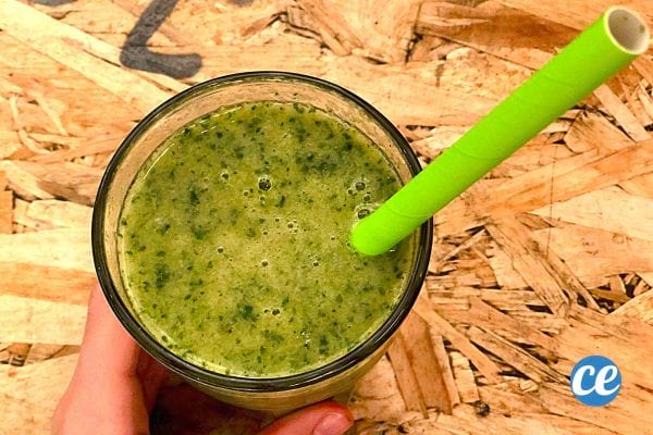 Un verre contenant du jus de Persil avec une paille verte à l'intérieur