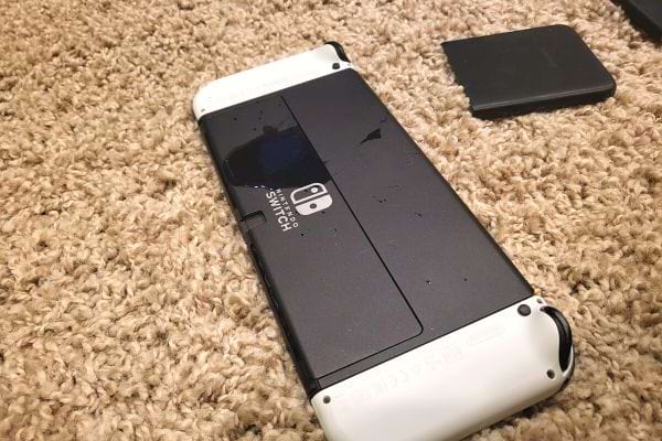 Ein schwarz-weißer Nintendo-Switch mit Flüssigkeit darauf liegt auf dem Teppich