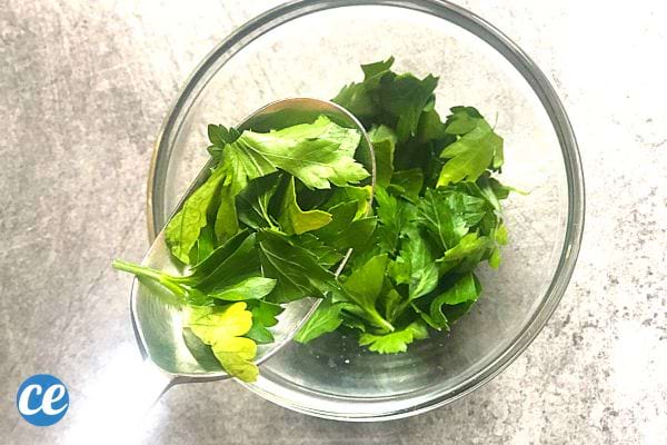Du Persil dans une cuillère à soupe au dessus d'un petit bol en verre