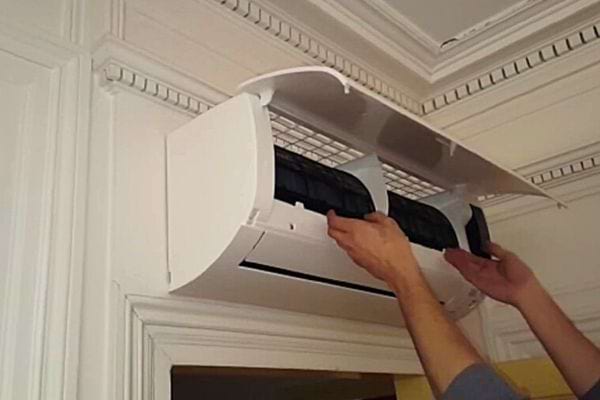 Une personne levant les bras vers une clim en hauteur