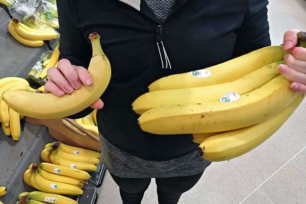 Une femme tenant plusieurs bananes dans un supermarché