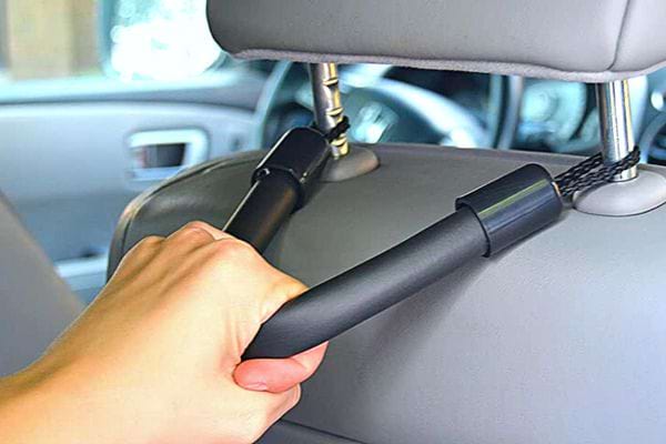 Une personne qui se maintien sur une poignet derrière un siège dans une voiture 