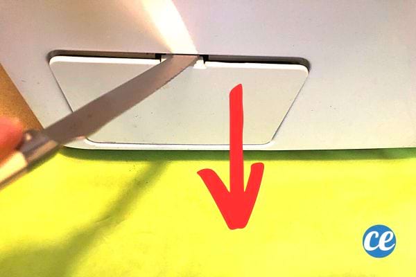 Une personne enlevant le cache où se trouve le filtre de la machine à laver