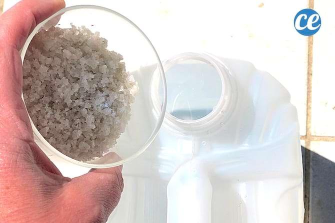 Une personne mettant du sel dans une grande bouteille blanche