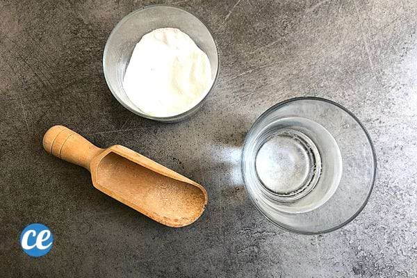 Deux verres avec un qui est remplie de bicarbonate et l'autre d'eau et ustensile en bois juste devant