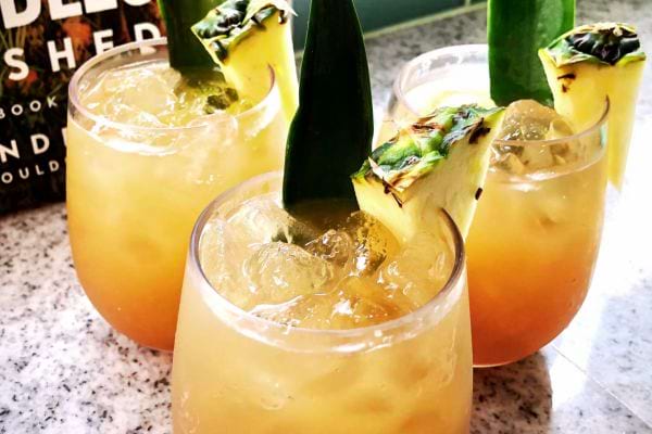 Trois verres contenant une boisson de couleur jaune avec des morceaux d'ananas sur le rebord