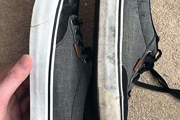 Une personne qui tient une paire de Vans sale et propre