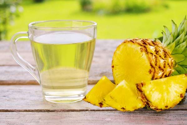 Un ananas coupé à côté d'un verre sur une table