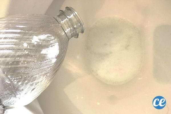 Du bicarbonate de soude avec une bouteille de vinaigre blanc dans des toilettes 