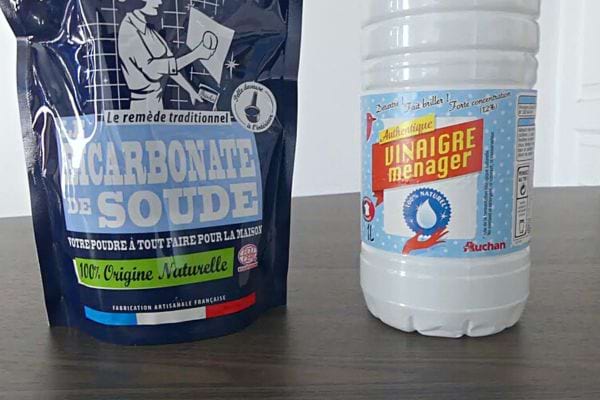 Un paquet de bicarbonate de soude bleu à côté d'une bouteille de vinaigre ménager