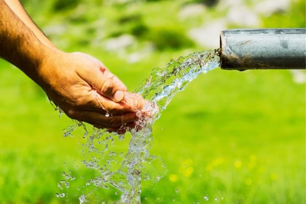 Un homme qui boit de l'eau d'une fontaine pour satisfaire ses besoins physiologiques selon la pyramide de Maslow