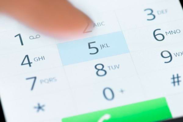 Une personne tapant sur le chiffre cinq dans la numérotation d'un numéro sur son téléphone