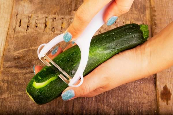 Une femme qui épluche une courgette