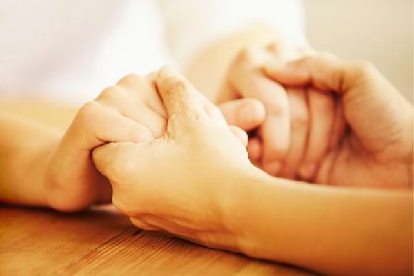 Des mains serrées entres elles pour décrire les besoins sociaux de la pyramide de Maslow