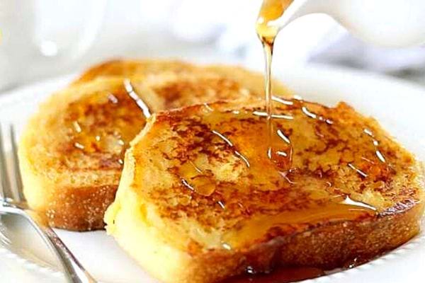Deux tranches de pain perdu avec du sirop dans une assiette blanche