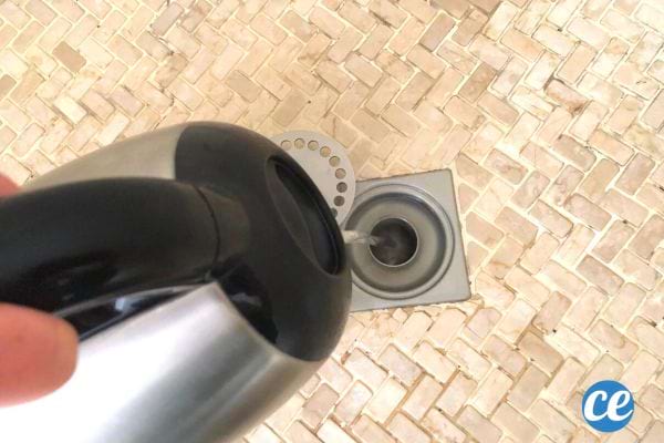 Une personne mettant de l'eau bouillante dans le trou d'une douche