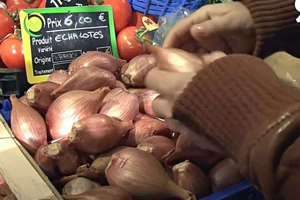 Une femme avec des échalotes dans un supermarché 