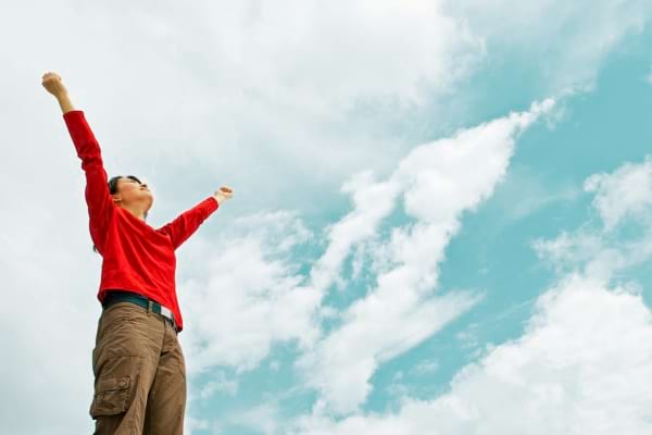 Une femme levant les bras ayant accompli ses besoins personnels selon la pyramide de Maslow