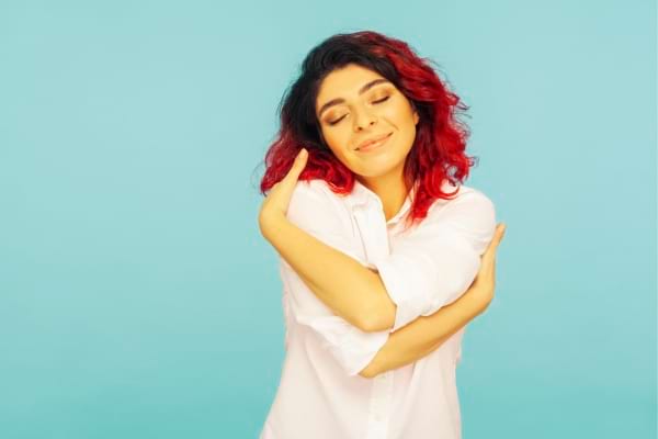 Une femme qui se serre dans ses bras pour montrer qu'elle s'estime 