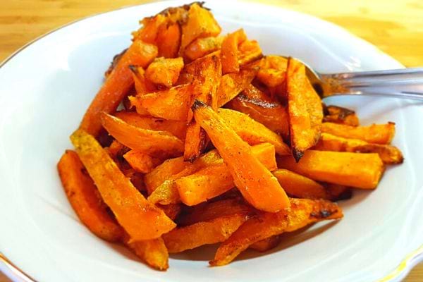 Une assiette blanche creuse remplie de frites de patates douces rôties au four