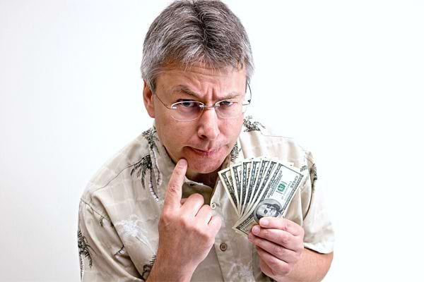 Ein Mann mit Brille und einem Bündel Dollars in der linken Hand