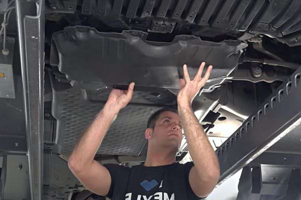 Ein Mann hält ein Autoteil in der Hand, um es zu warten