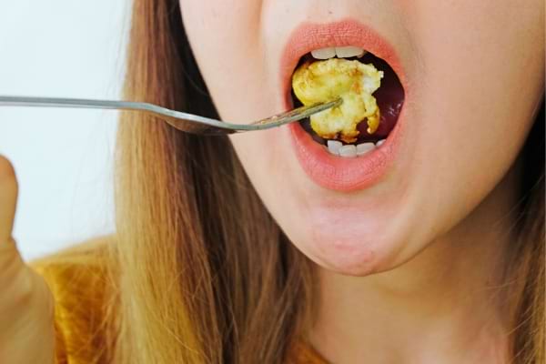 Une femme qui mange bouche ouverte en faisant du bruit pour mieux apprécier les aliments