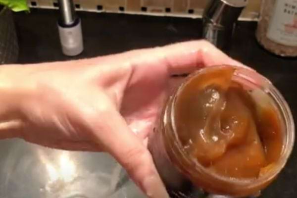 Une personne tenant un pot contenant du savon noir