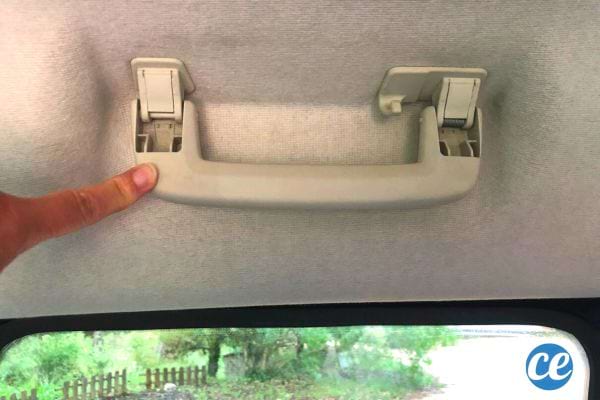 Eine Person senkt den Haltegriff in einem Auto