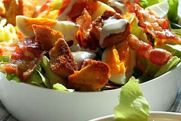 Une assiette blanche de salade au bacon