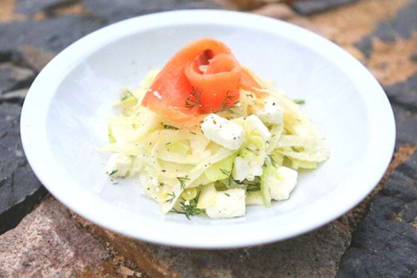 Une assiette blanche de salade de fenouil au saumon fumé et à la feta