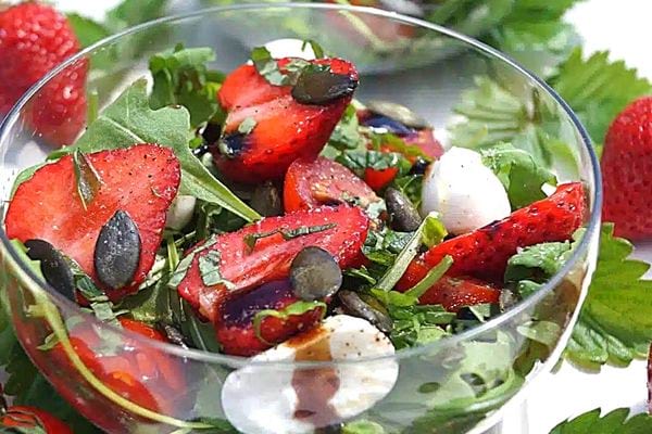 Un bol de salade de fraises, roquette et mozzarella