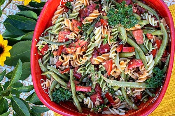 Une assiette rouge de salade de pâtes au thon et haricots verts