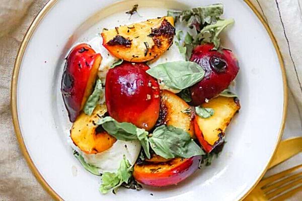 Une assiette blanche de salade pêches mozzarellade